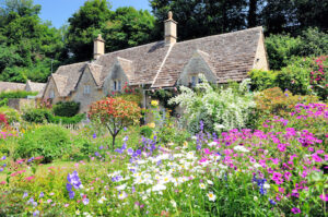 Colorful garden enveloping a traditional cottage in England's beautiful Cotswold region. Image credit: Shutterstock